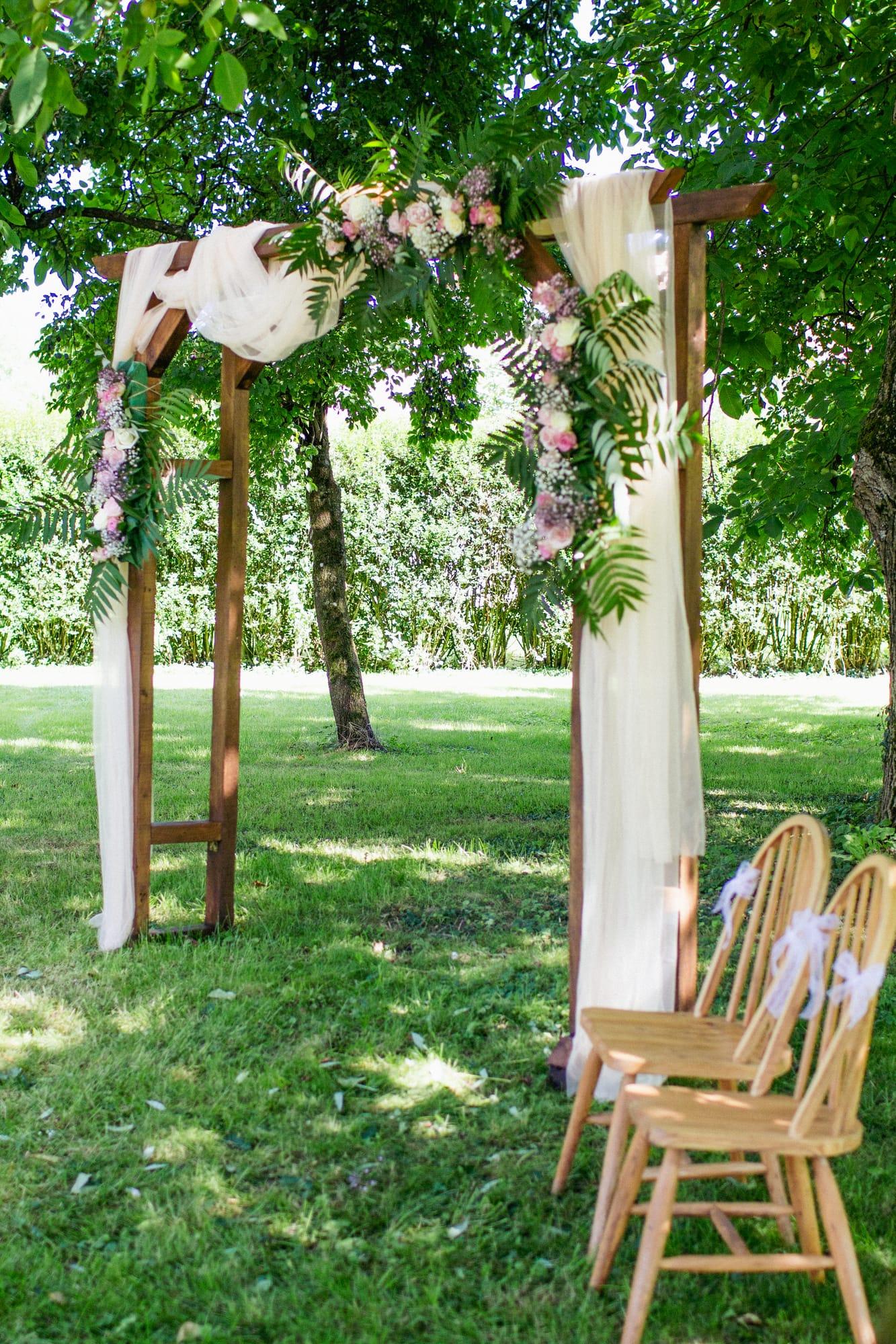 Arche de cérémonie en bois, fleurie et drapée de voilages