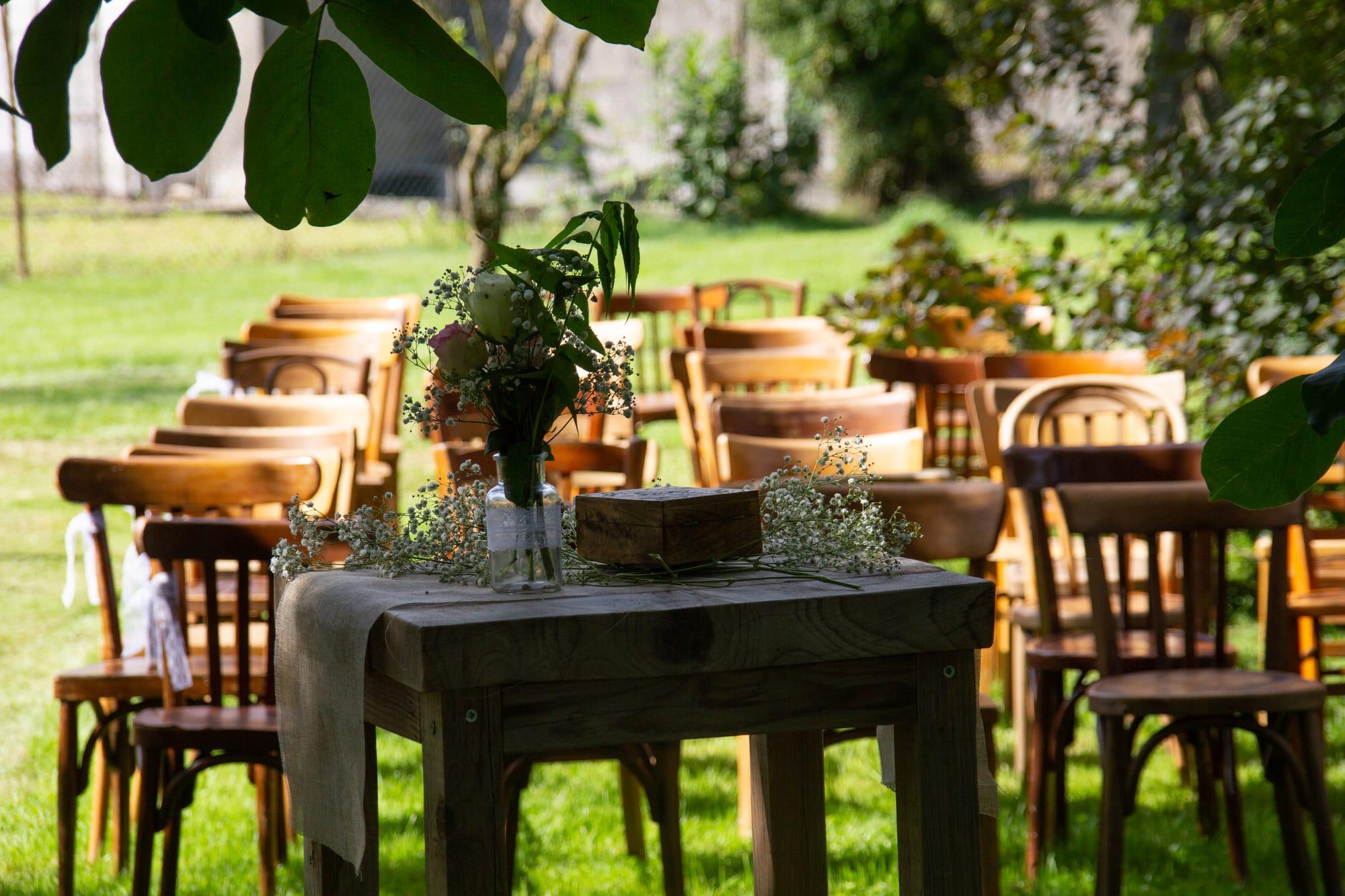 Table de cérémonie fleurie devant les rangées de chaises en bois